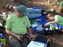 Star Scout Mason Turner, KK4HOR, checks out some gear while Scoutmaster Chris Anderson makes a contact in Canada using his Yaesu FT-857D transceiver and Buddipole antenna while backpacking in Ocala National Forest. Assistant Scoutmaster Ryan Smith, KK4JLG, listens in. [Karen Anderson, KK4ENM, photo]